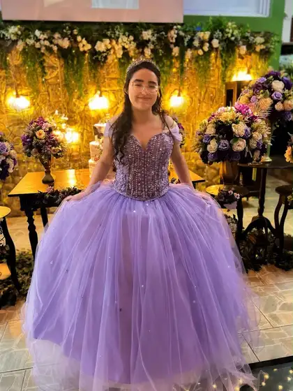 Debutante com vestido lilás diante do painel de flores