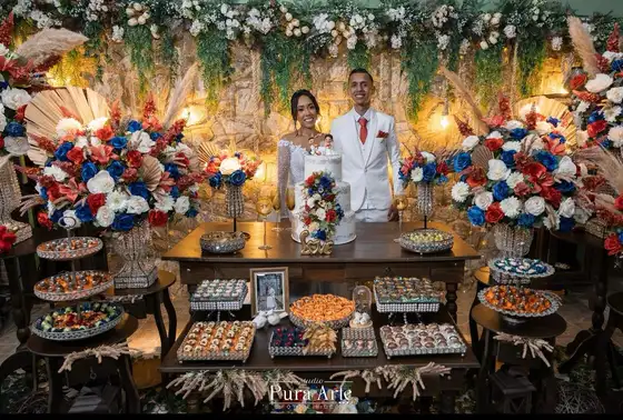 Mesa de doces com flores e painel de folhagens