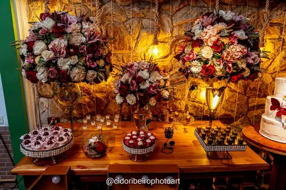 Mesa de doces diante da parede de pedra iluminada